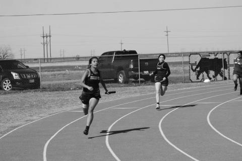 Aliyah DePoyster of Wellman-Union (left) and J’Me Garcia of Meadow compete in the Girl’s 2x200-meter relay at the District 5-1A Championships on Wednesday at Wellman-Union High School.