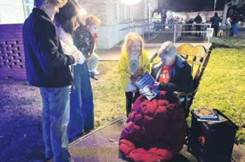 Gina Kelly, seated, starts to read a Christmas story to guests after the Christmas Light Parade. There were also cookies and hot chocolate served after the event.